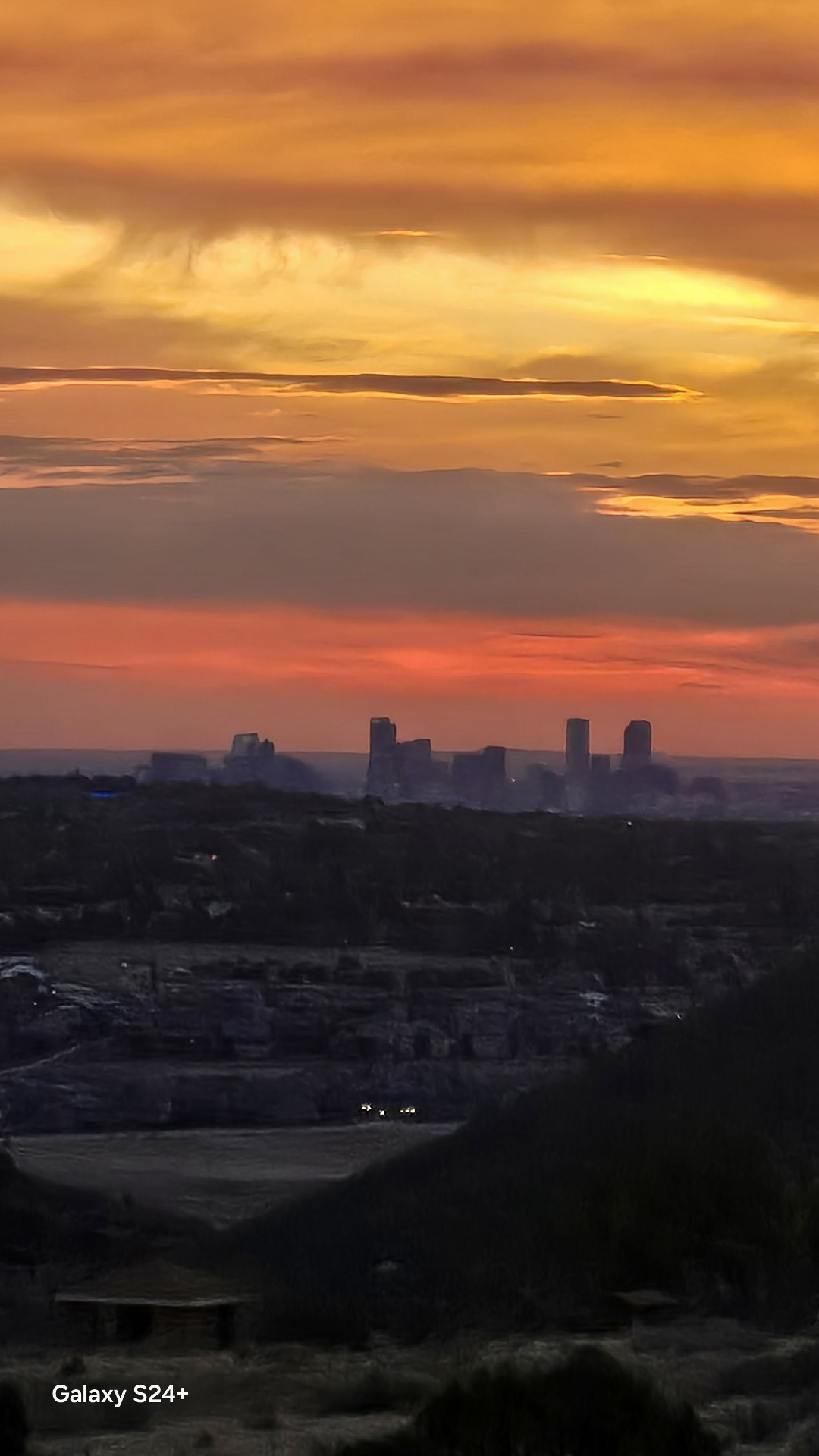Fiery sunrise sky with downtown Denver skyline in the distance from Mt. Falcon